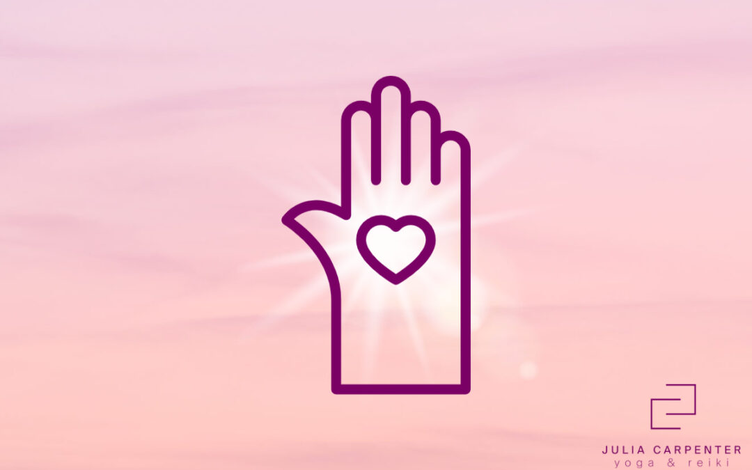 hand with heart in the center in front of pink sky background